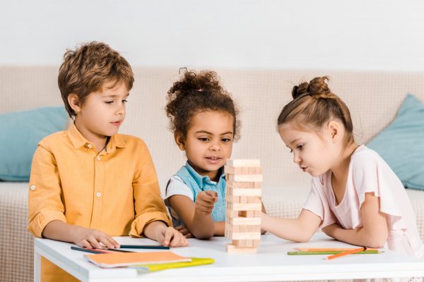 cute little multiracial children playing with wooden blocks on table